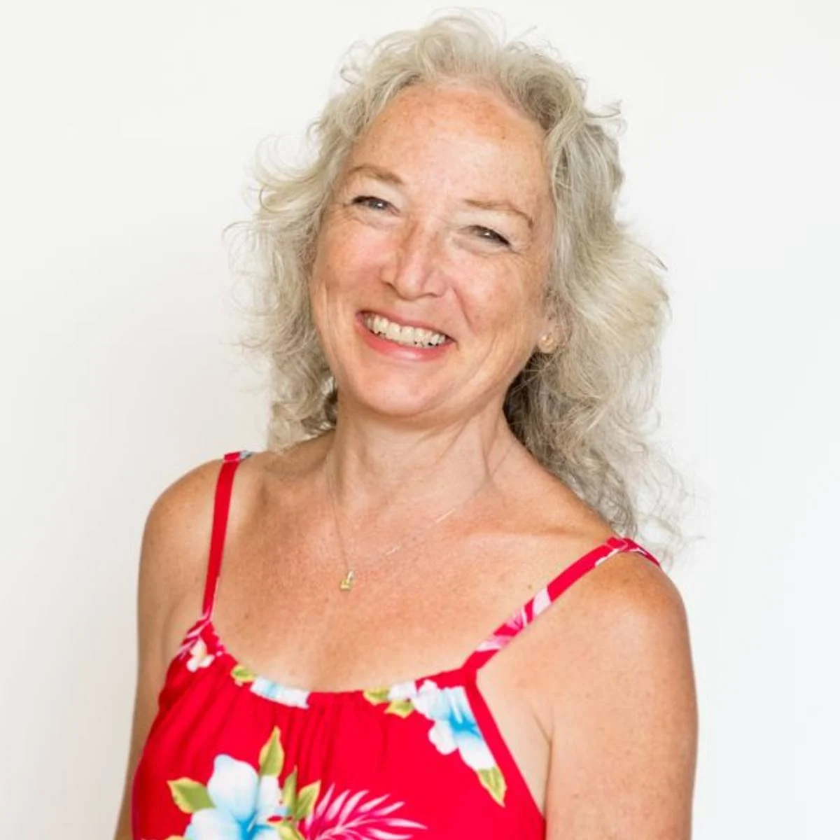 Georgie Hunter, Realtor, smiling in a red hibiscus-print dress