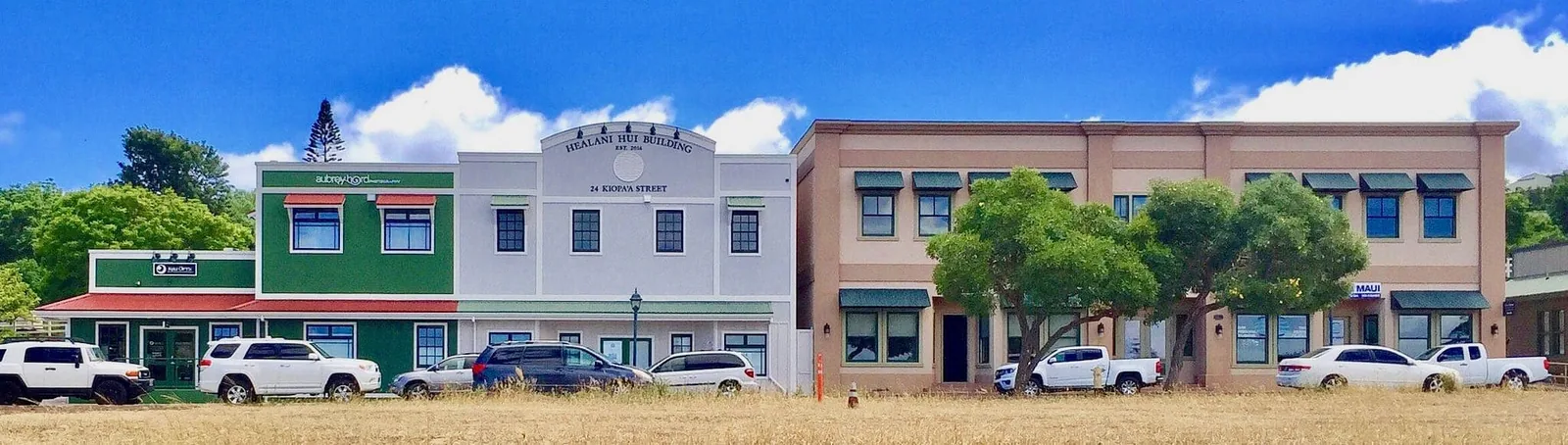 Kulamalu Town Center in Pukalani, green and tan plantation-style buildings with a golden-grass foreground